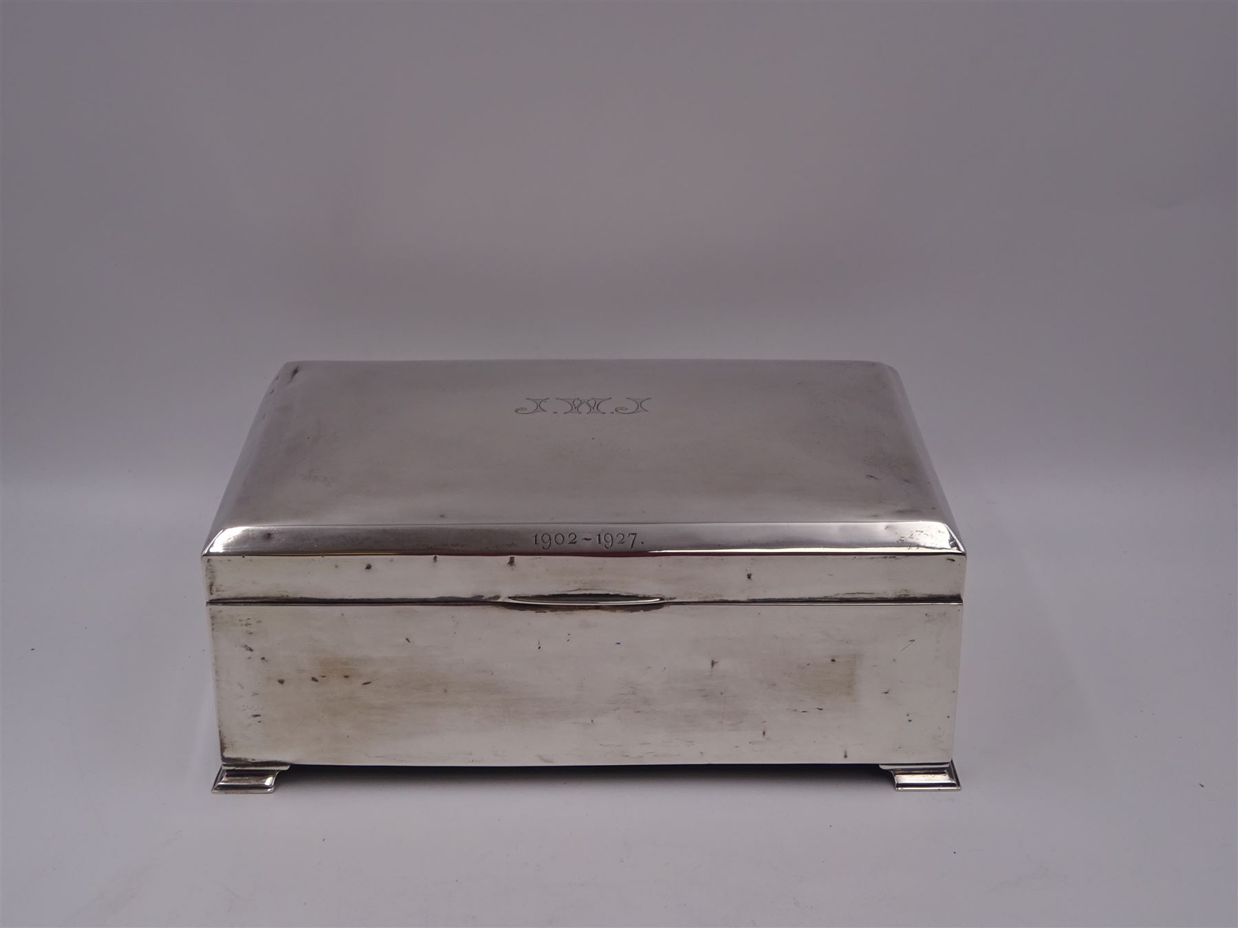 1920s silver mounted presentation cigarette box, of rectangular form, with engraved initials J.W.J and dated 1902-1927 to slightly domed hinged cover, opening to reveal compartmentalised softwood interior, upon four bracket feet, hallmarked Birmingham 1920, maker's mark worn and indistinct, H9cm, W23cm, reputedly given to John William Johnson, father of Amy Johnson,  famous for being the first long distance (to Australia) solo female pilot, and first female British grounds engineer, for his silver wedding anniversary
