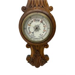 A carved oak cased aneroid barometer with a 5” register, measuring barometric pressure from 26 to 31.9 inches, weather predictions written in gothic capitals and lower-case script, with a steel indicating hand and brass recording hand within a brass bezel with a flat bevelled glass, with a mercury thermometer recording the temperature in degrees Fahrenheit and Celsius.



