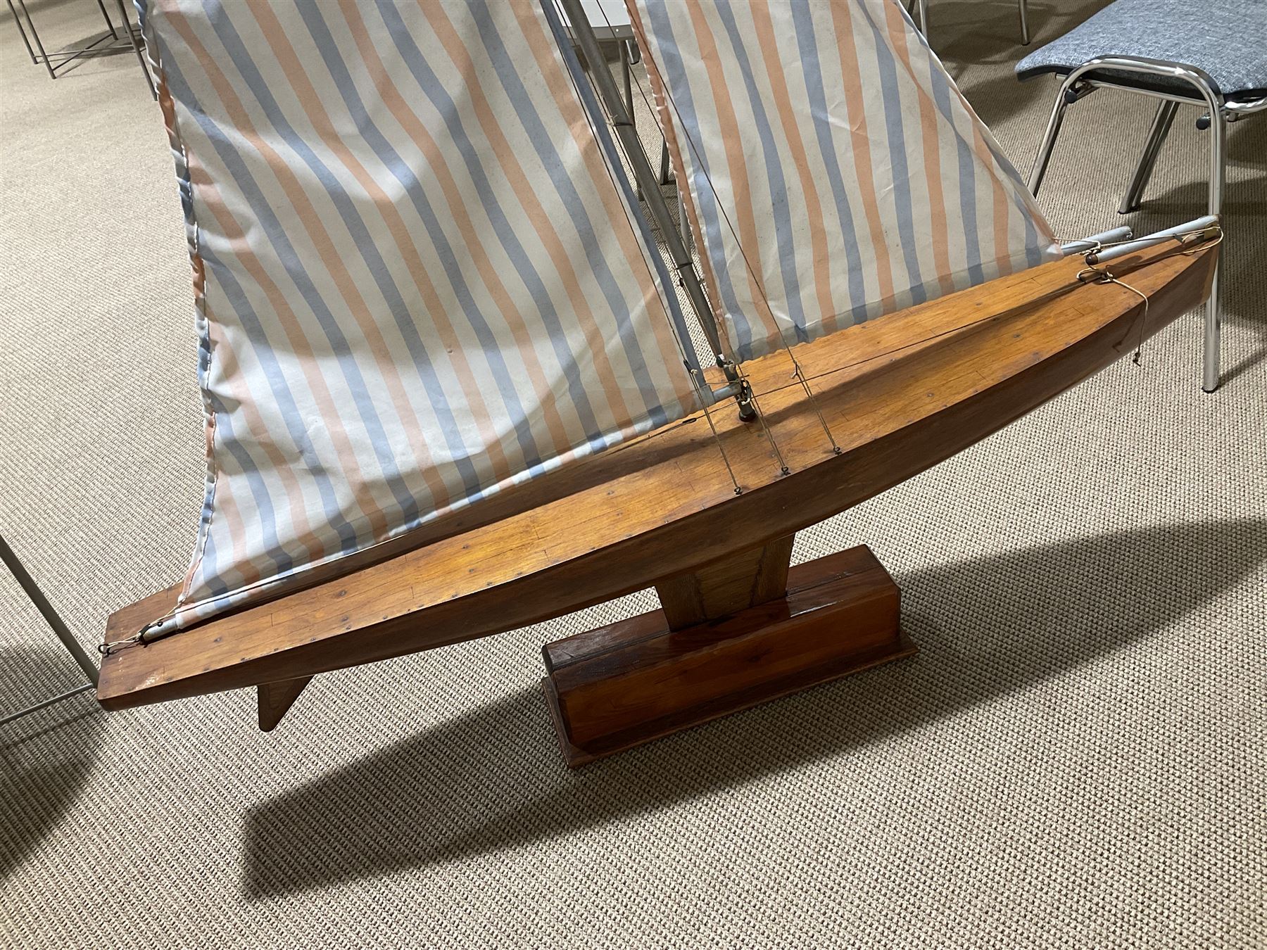 Large pond yacht with simulated planked mahogany deck, mahogany hull, wooden keel and stern fin and tubular aluminium mast with two sails; on wooden stand L131cm H on stand 177cm