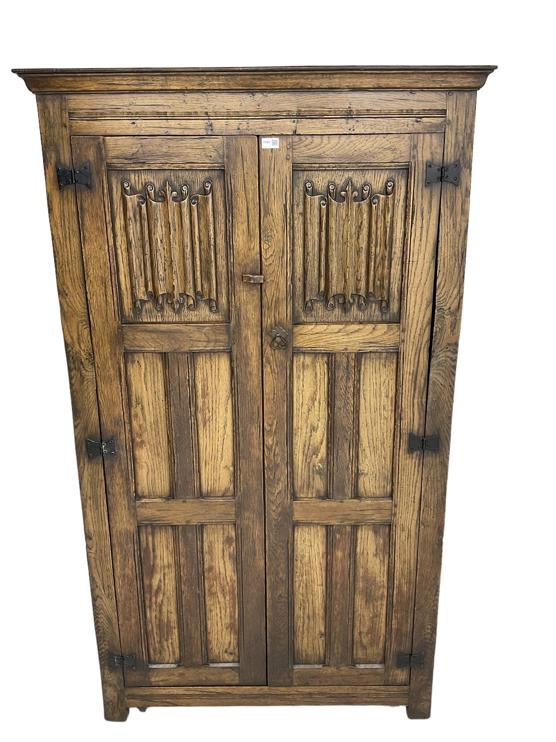 Mid-to-late 20th century oak double wardrobe, enclosed by panelled doors with linenfold decoration