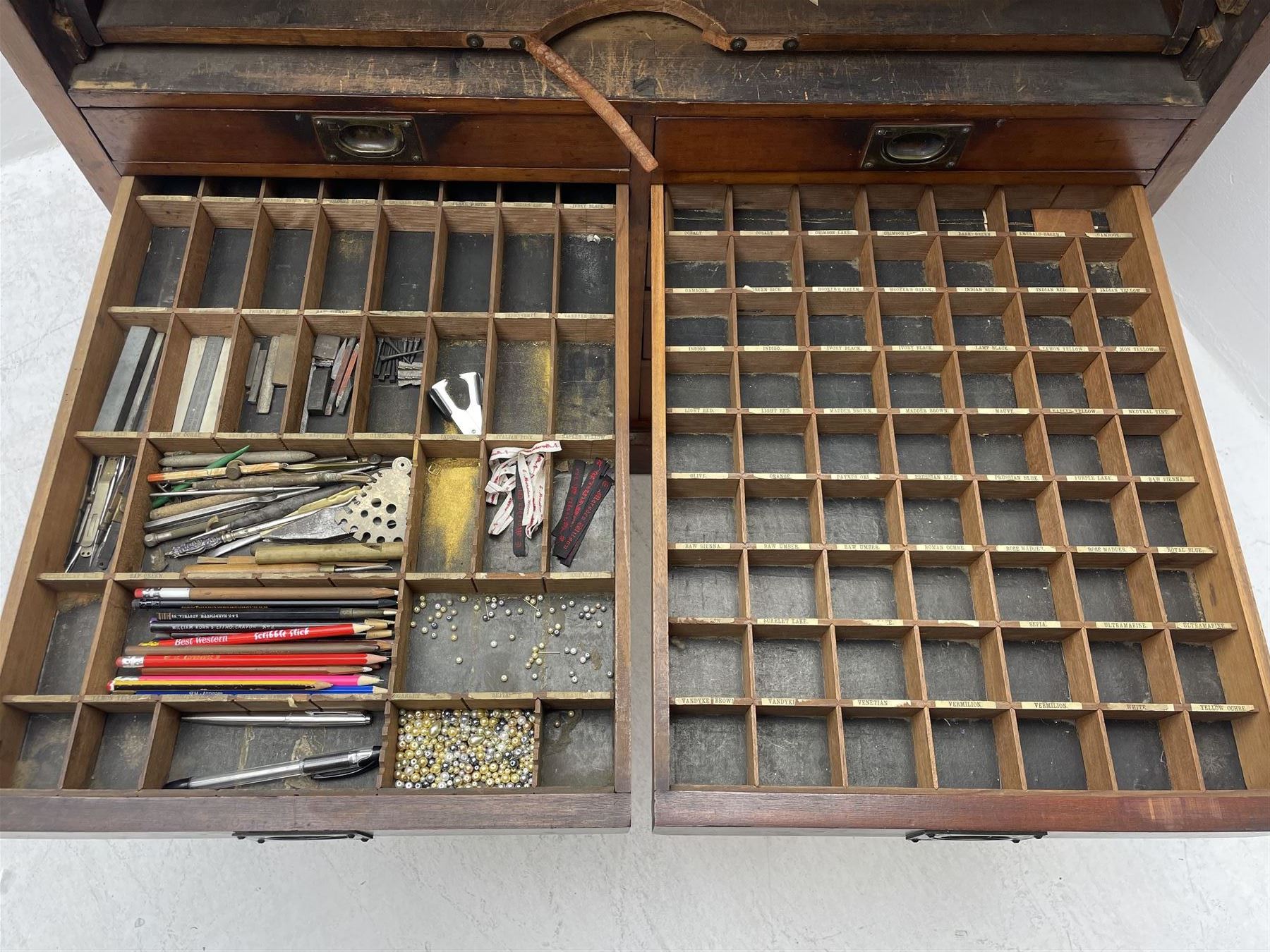 Edwardian mahogany artist's cabinet once belonging to the British artist Eli Marsden Wilson (1877-1965), raised panelled back mounted by carved brackets, sloped and hinged glazed lid enclosing paint holders and compartments, up-and-over panelled door revealing three slides, fitted with two banks of five graduating drawers with recessed brass handles, on skirted base.

Together with a quantity of artists' equipment and tools including paints, paintbrushes, charcoal, chalks, etc. and various prints relating to the life of the artist, including Quaker anti-war posters, Victorian Stevengraphs, and various chromolithographs 

Provenance: Removed from the studio of Eli Marsden Wilson. The cabinet comes to us for sale through family descent. The vendor is descendant of Marsden. Many further etchings removed from the cabinet are being sold in the Spring Art Sale, Friday 15th March 2024, Lots 265-271.

Notes: born in Ossett, Eli Marsden Wilson was the only son of Alfred Wilson, a foreman beamer, and Emma Marsden, and had five sisters. After studying at Wakefield College of Art, he moved to the Royal College of Art in London, where he became a pupil of Sir Frank Short. He had his first exhibit at the Royal Academy in 1905, the same year he married fellow artist Hilda Mary Pemberton.

A Quaker, vegetarian, and pacifist, he was a conscientious objector in World War I and as such was imprisoned in 1917 for two years. In September 1922 he was commissioned by Princess Marie Louise to produce miniature etchings for Queen Mary's Dolls' House at Windsor Castle; two such etchings are being sold in the Spring Art Sale, Friday 15th March 2024, Lot 265.