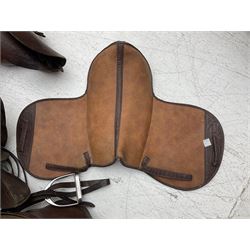 Collection of eight saddles, mainly havana leather, some with stirrups and leathers 