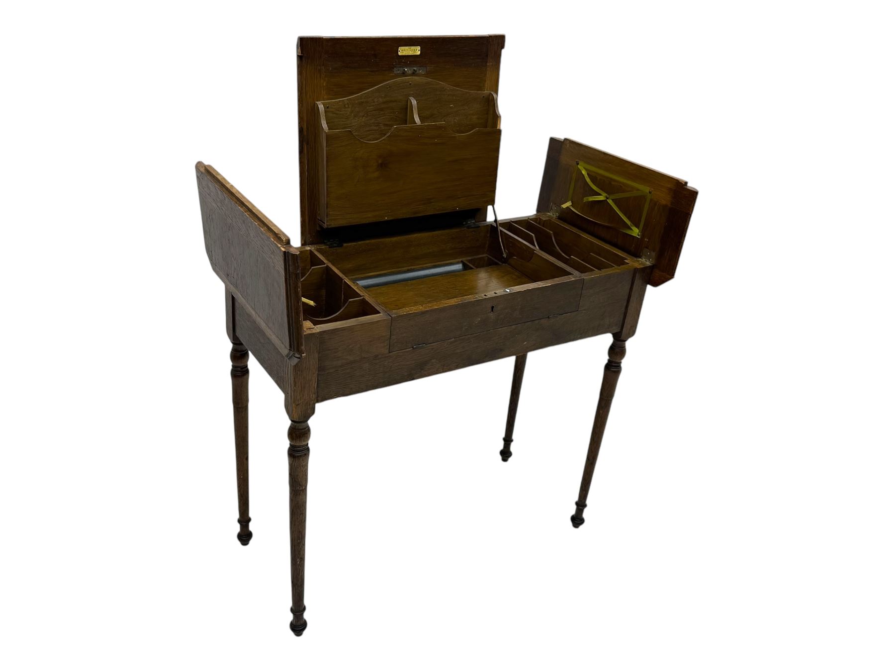 Edwardian oak metamorphic 'Britisher Writing Table', rectangular hinged top revealing correspondence compartments and hinged writing surface with underside storage, flanked by twin hinged compartments with dividers, on turned supports