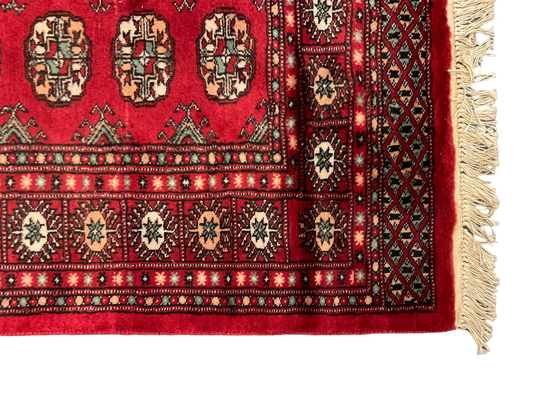 Persian Bokhara crimson ground rug, the field decorated with repeating Gul motifs and lozenges, the multi-band border with stylised plant motifs with black outlines