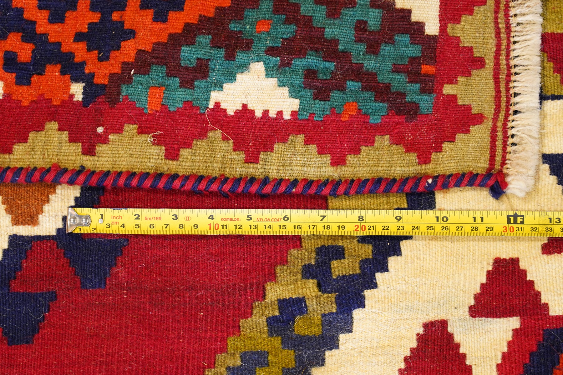 Persian Qashqai crimson ground rug, the central narrow ivory field decorated with repeating hooked geometric lozenges in multicolours, with a densely decorated guard band