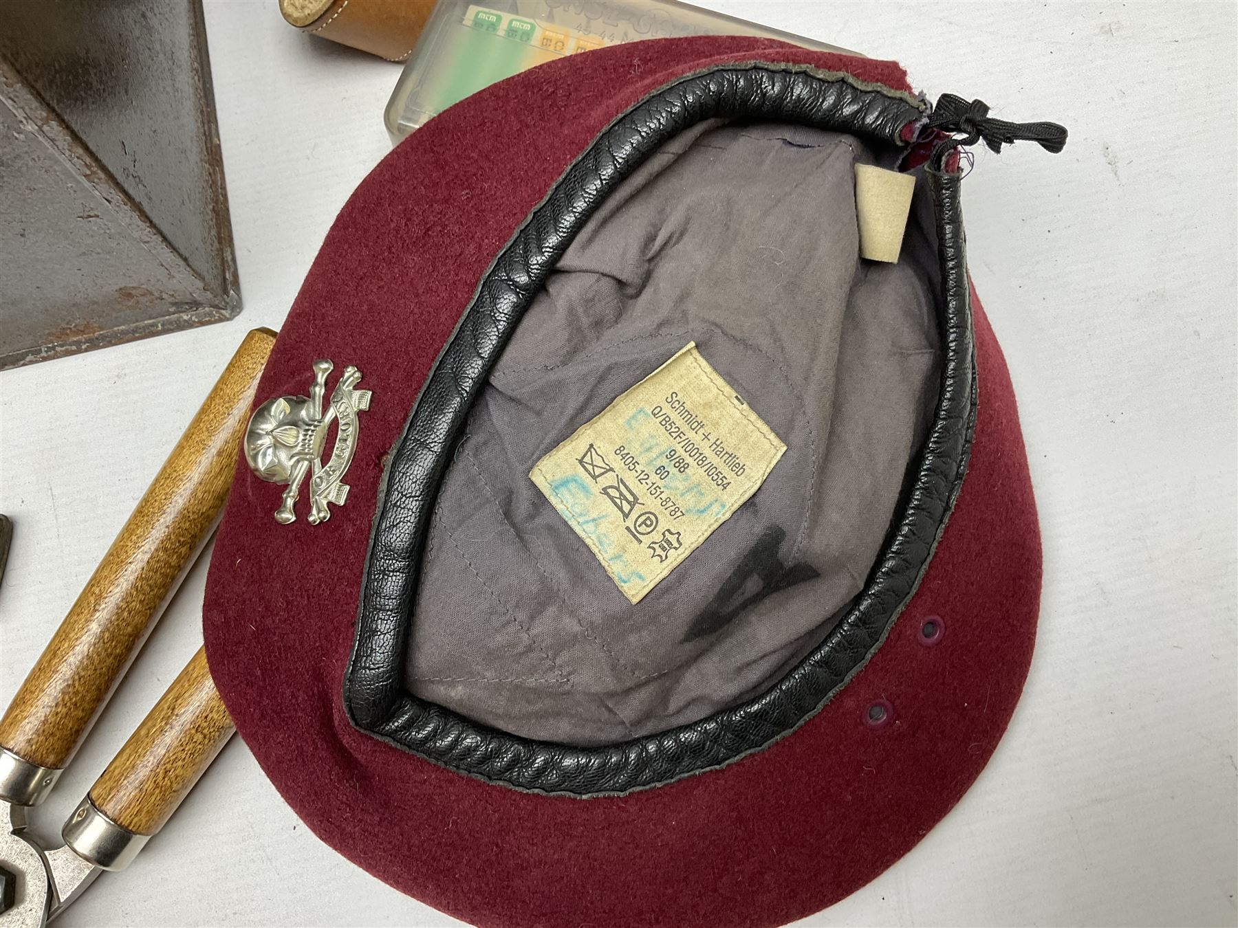Assorted militaria including ten leather or canvas cartridge and other belts, maroon beret with 17th Lancers cap badge, modern bullet mould, leather and brass shot flask, two knives, shell cases, boomerang etc; in tin deed box