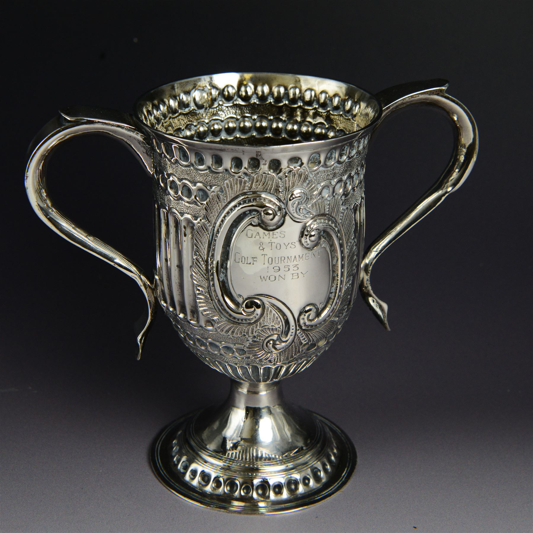 George III silver twin handled trophy cup, of typical form with twin C scroll handles and upon a domed circular foot, the body with repousse and chased fluting and C scroll decoration, with later presentation engraving to cartouche, hallmarked London 1803, maker's mark slightly rubbed but probably for Peter, Ann and William Bateman, H16cm