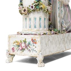 Large19th century  German porcelain mantel clock with white dial and striking movement, the case with a standing figure of Flora resting on a pillar with floral applied decoration, the base painted eith landscape and floral panels on paw feet H77cm W43cm