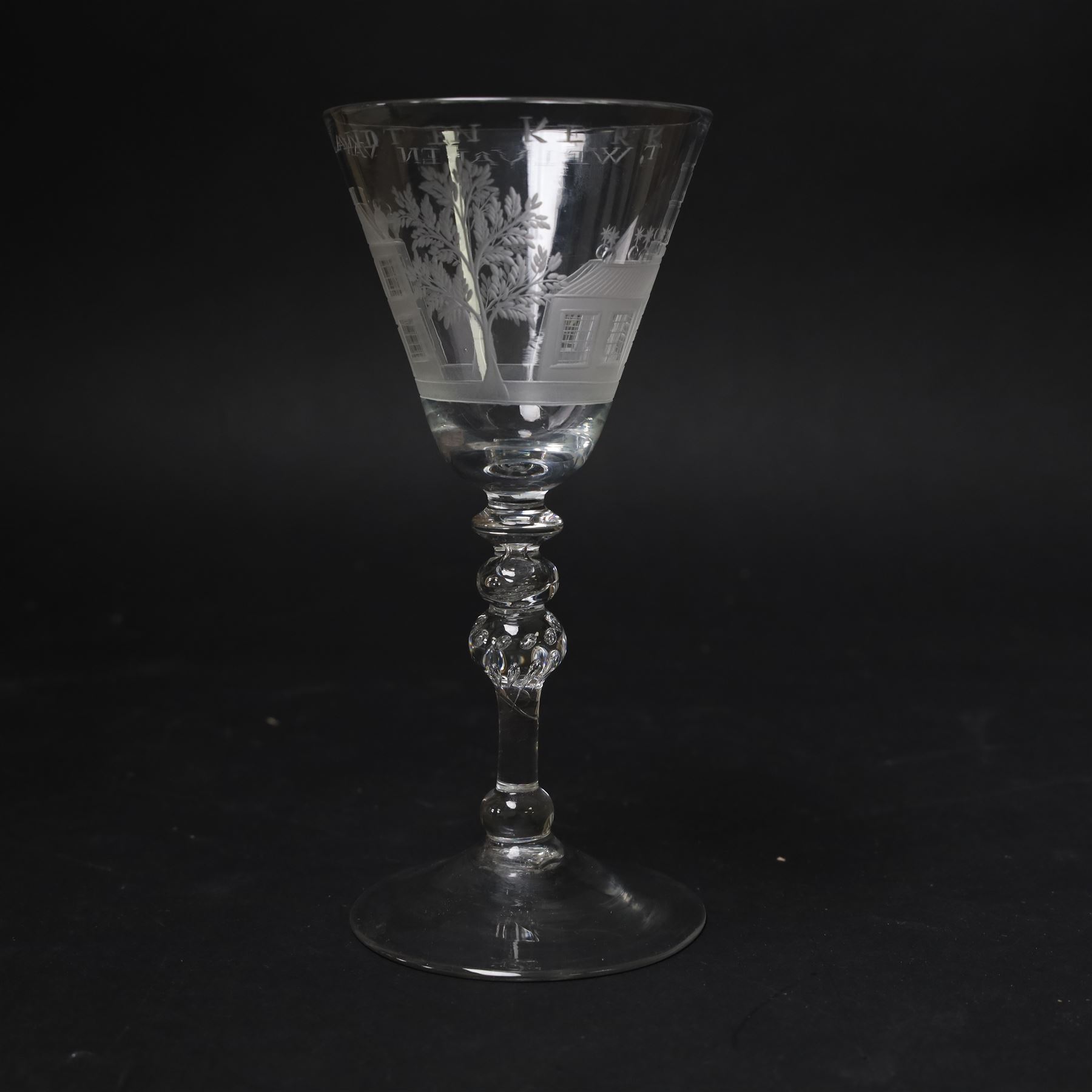 Dutch engraved Newcastle light baluster glass, circa 1760, the funnel bowl engraved with a two storey country house and church flanked by trees, beneath the inscription ‘T WELVAREN VAN LANDT ENKERK’ (The prosperity of the Country and Church), upon a multi knopped stem with beaded knop and basal knop, over conical foot, H18cm



