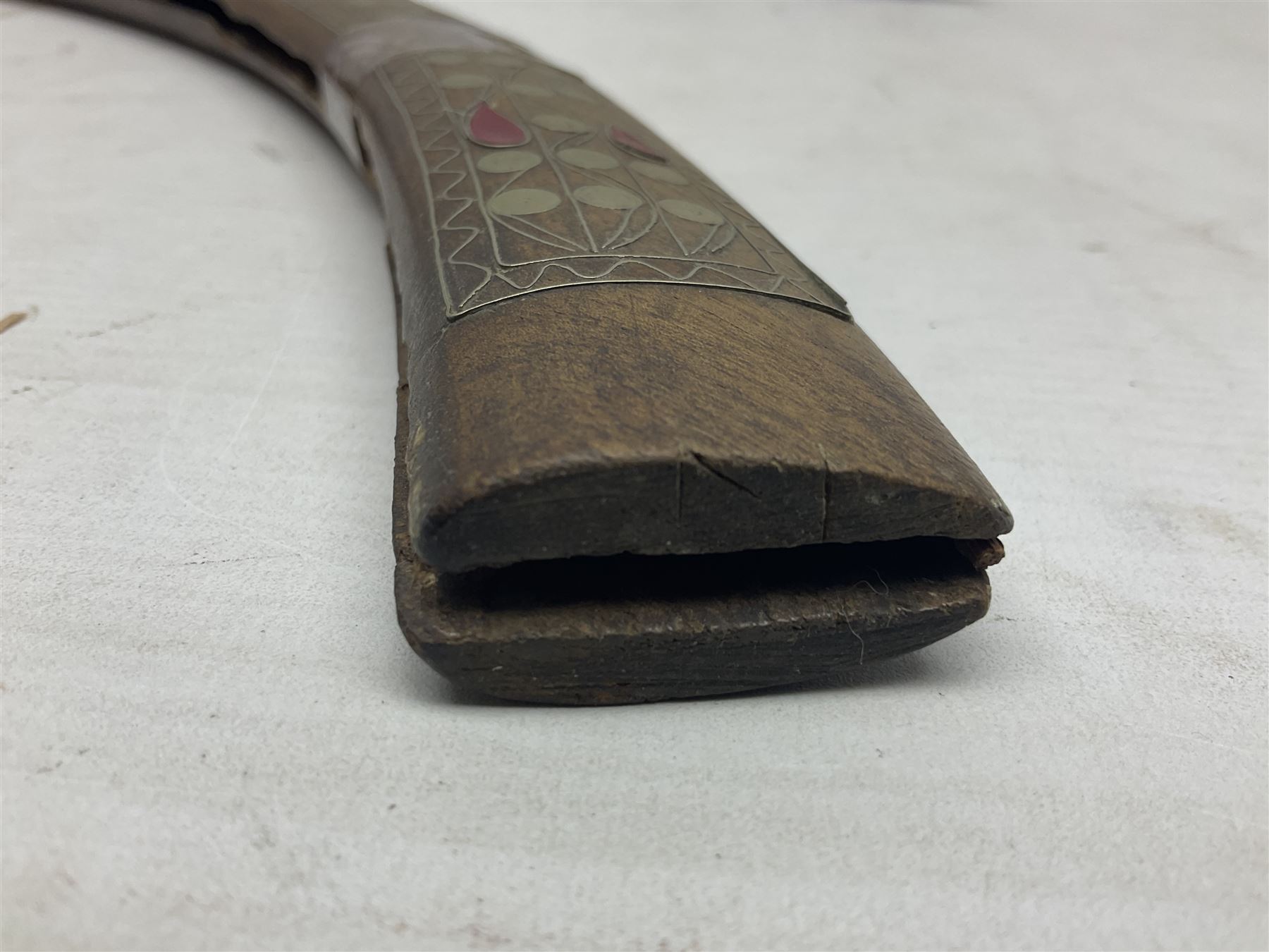 Late 19th/early 20th century Moroccan nimcha dagger-sword, the 40cm curving steel blade with engraved decoration on both sides; shaped hardwood hilt inlaid with brass, white metal wires and red coloured panels; in similarly inlaid scabbard L61cm overall