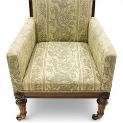 William IV rosewood framed library armchair, squared form with green on ivory ground upholstery, moulded lower seat rail with applied roundels over reeded supports, terminating to brass cups and castors