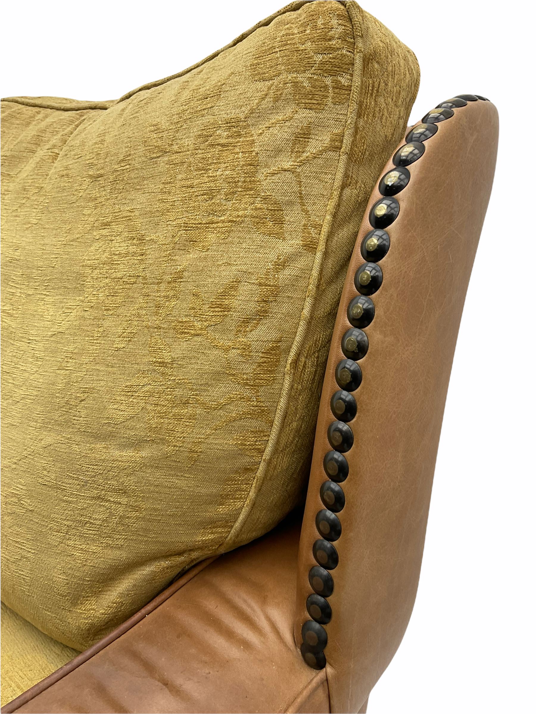 Pair of 1930’s carved oak framed club chairs, upholstered in tan studded leather with beige fabric loose cushions