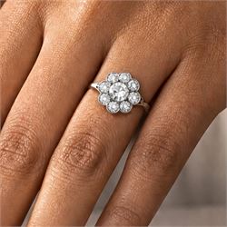 Early 20th century platinum diamond daisy flower head cluster ring, principal round cut diamond of approx 0.65 carat, surrounded by eight milgrain set old cut diamonds, within a pierced scroll design gallery, total diamond weight approx 2.15 carat