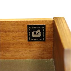 Alfred Cox - mid-20th century teak cabinet, rectangular top over two bifold doors with inset handles, opening to reveal three central graduating drawers surrounded by assorted shelves, raised on tapering supports united by H-stretcher, stamped to inside of drawer