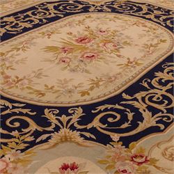 20th-century Aubusson-style woven tapestry wall hanging of rectangular form, the design with a central oval floral medallion composed of delicate sprays in soft pinks, creams, and muted green enclosed by an elaborate dark blue scrolling acanthus ground enriched with foliate ornamentation, field framed by floral cartouches to the corners and multiple guard borders in pale blue, ivory, and ochre tones