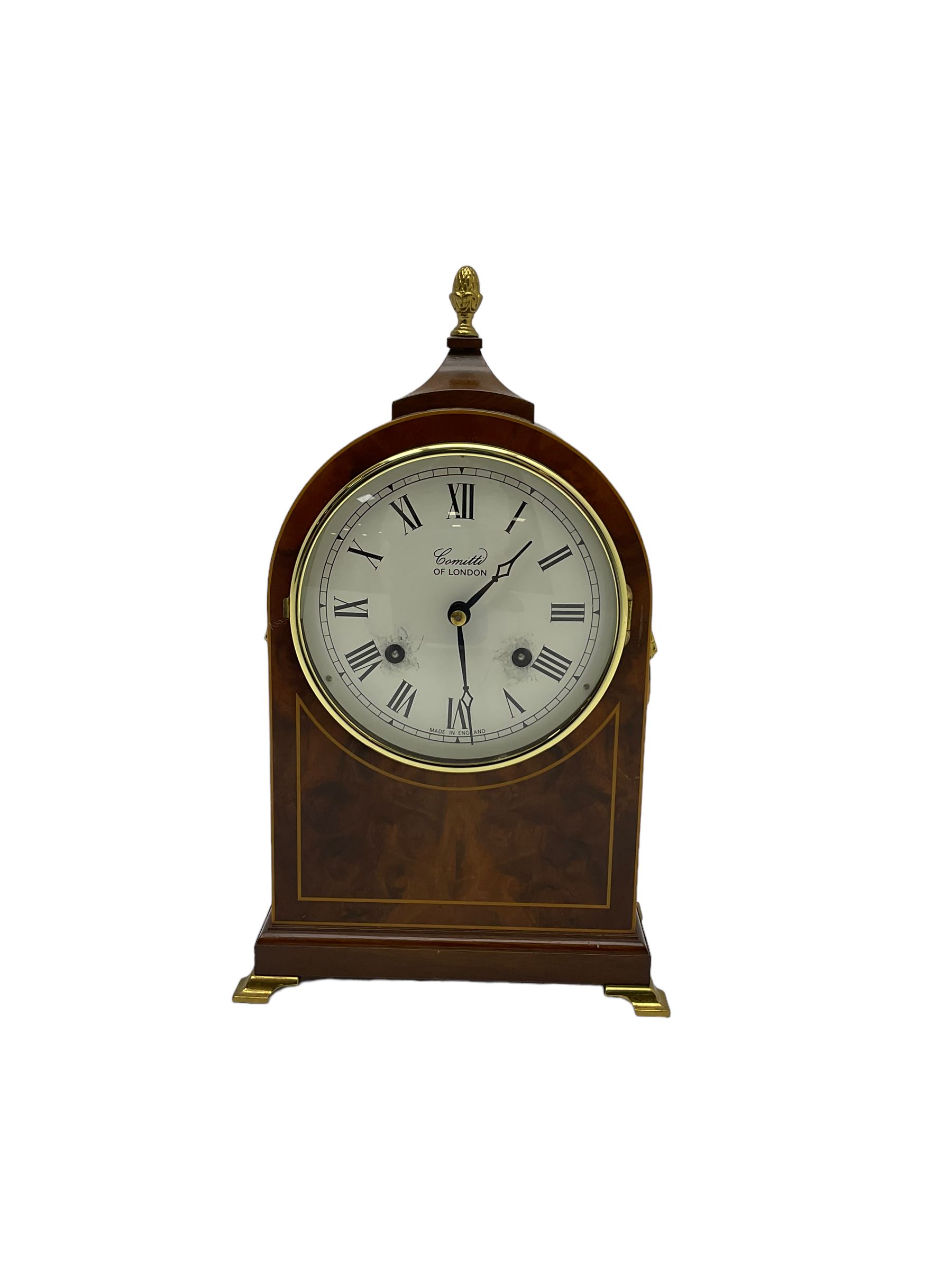 Comitti of London - 20th century 8-day mantle clock, in classic round topped mahogany case with inlaid stringing to the front and lion mask handles to the sides, raised on a narrow plinth with bracket feet, twin train going barrel movement with a floating balance escapement, striking the hours and half hours on a bell.    