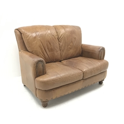 Three seat sofa upholstered in studded tan leather, turned supports (W194cm) and matching two seat sofa (W140cm) and footstool 