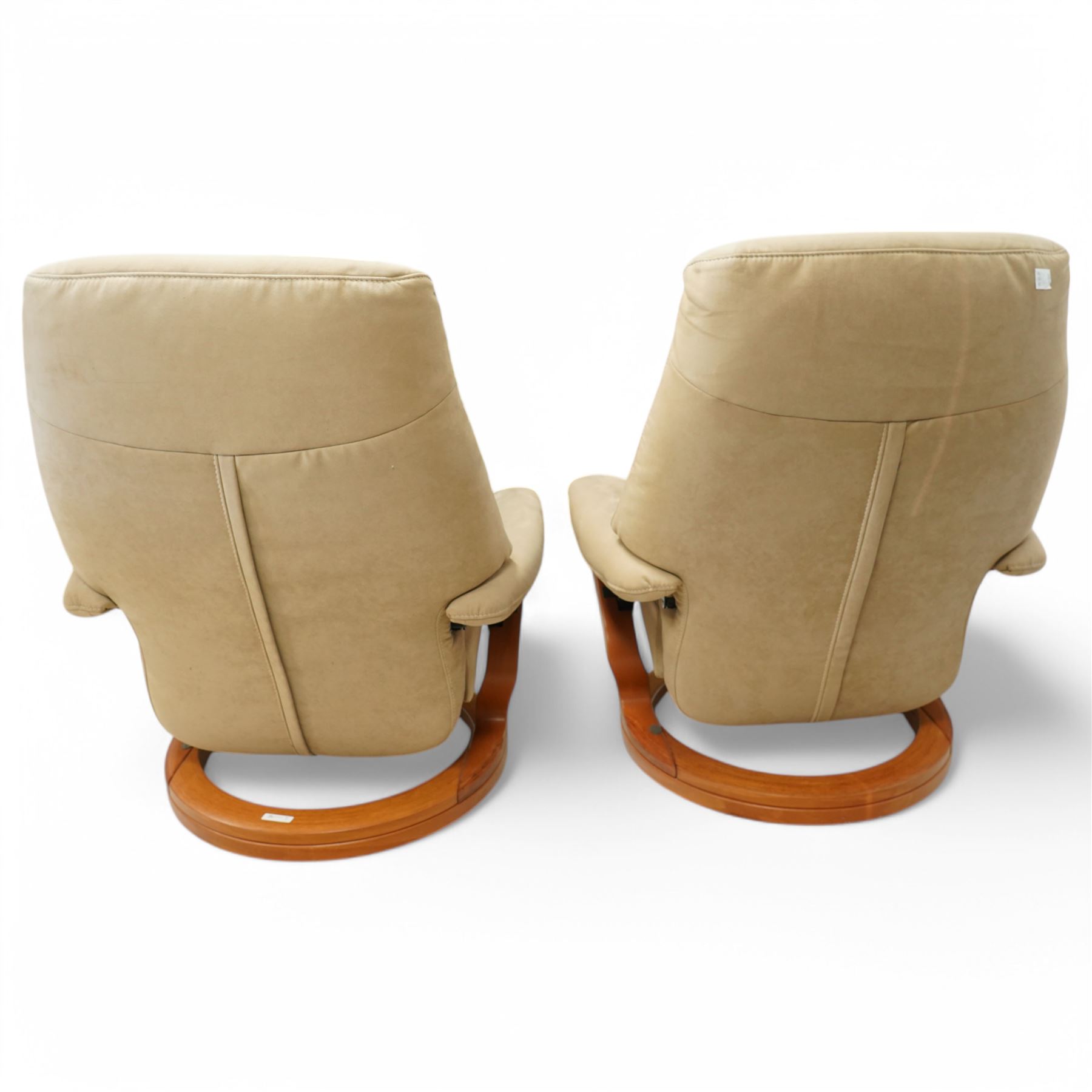 Himolla - A pair of swivel reclining chairs, beige upholstered with padded arms and high back rest, raised on a laminated circular wooden base with swivel mechanism 