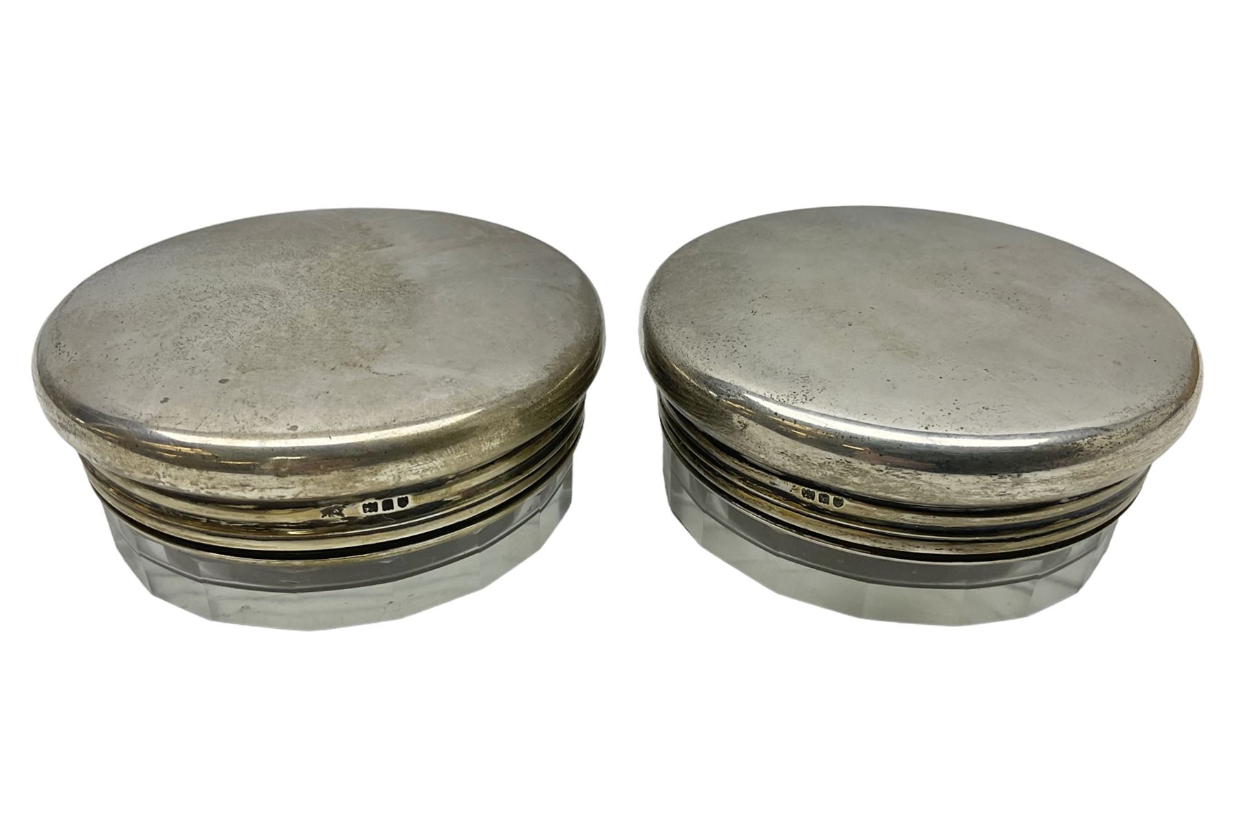 Pair of early 20th century glass dressing table jars, or circular facet cut form, with silver covers, hallmarked London, probably 1912