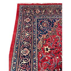 Persian Mahal crimson ground carpet, the field decorated with a central floral pole medallion, surrounded by scrolling foliate patterns and palmettes, the guarded indigo border with interlaced plant motifs
