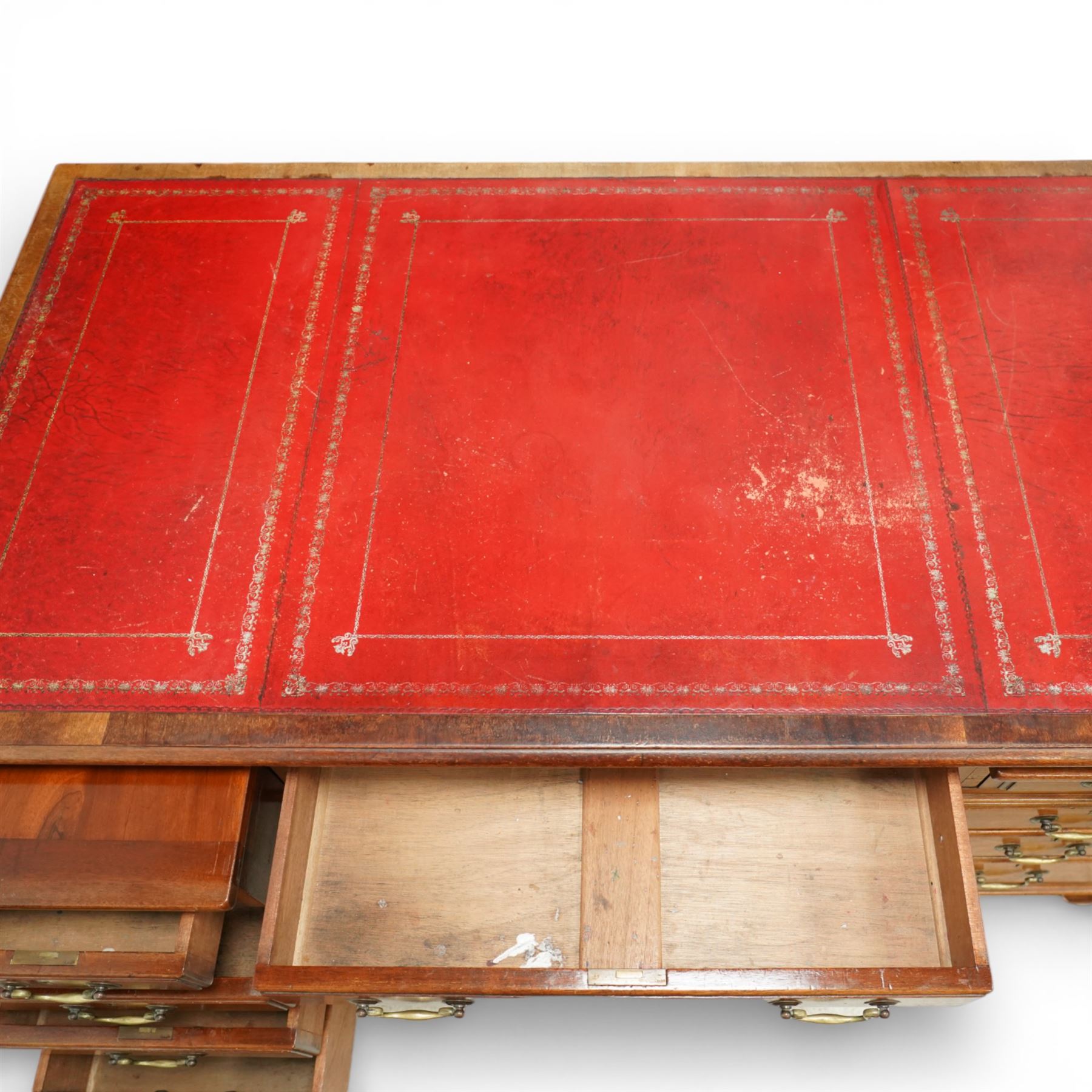 Late 19th century mahogany pedestal desk, rectangular top inset with worn red leather writing surface with gilt tooling, three frieze drawers above opposing pedestals each fitted with four graduated drawers, brass swan neck handles and escutcheons, panelled sides and back, raised on turned feet