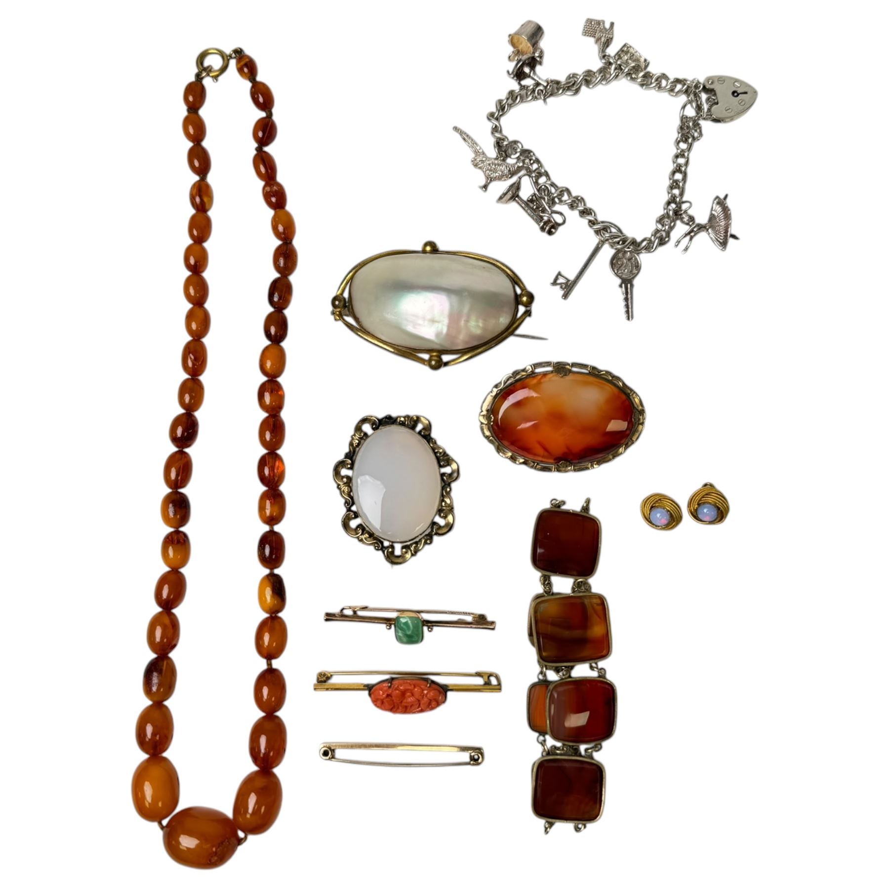 Three 9ct gold brooches, including two stone set examples, silver charm bracelet, amber type beads and gilt metal jewellery