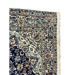 Persian Nain indigo and ivory ground rug, central pointed medallion within a field of scrolling branch and stylised floral motifs, repeating scrolled border with stylised plant motifs