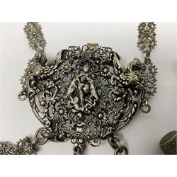 19th century continental silver plated chatelaine, the main body flanked with winged mythical beasts and central soldier slaying a dragon supporting three suspended items to include velvet lined small basket and long clasped filigree chain, together with a thimble