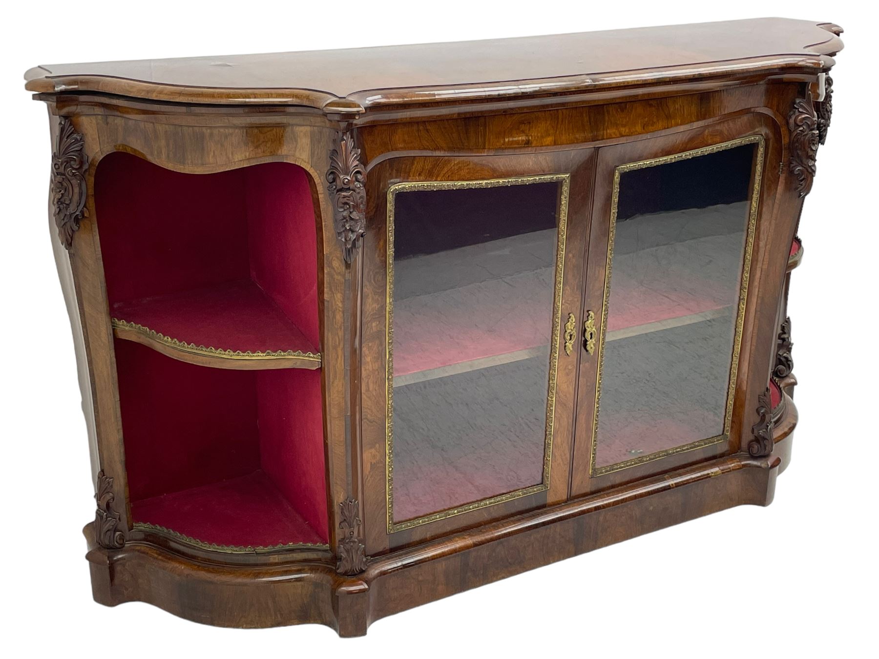 19th century rosewood buffet credenza, bombe form with shaped and moulded top, two central glazed doors with foliate moulded gilt slips, the red fabric-lined interior fitted with a single shelf, flanked by open shelves with raised gilt metal lips, the uprights decorated with shell and flower head carved cartouche mounts, acanthus leaf scroll carved lower mounts, on shaped and moulded plinth base 