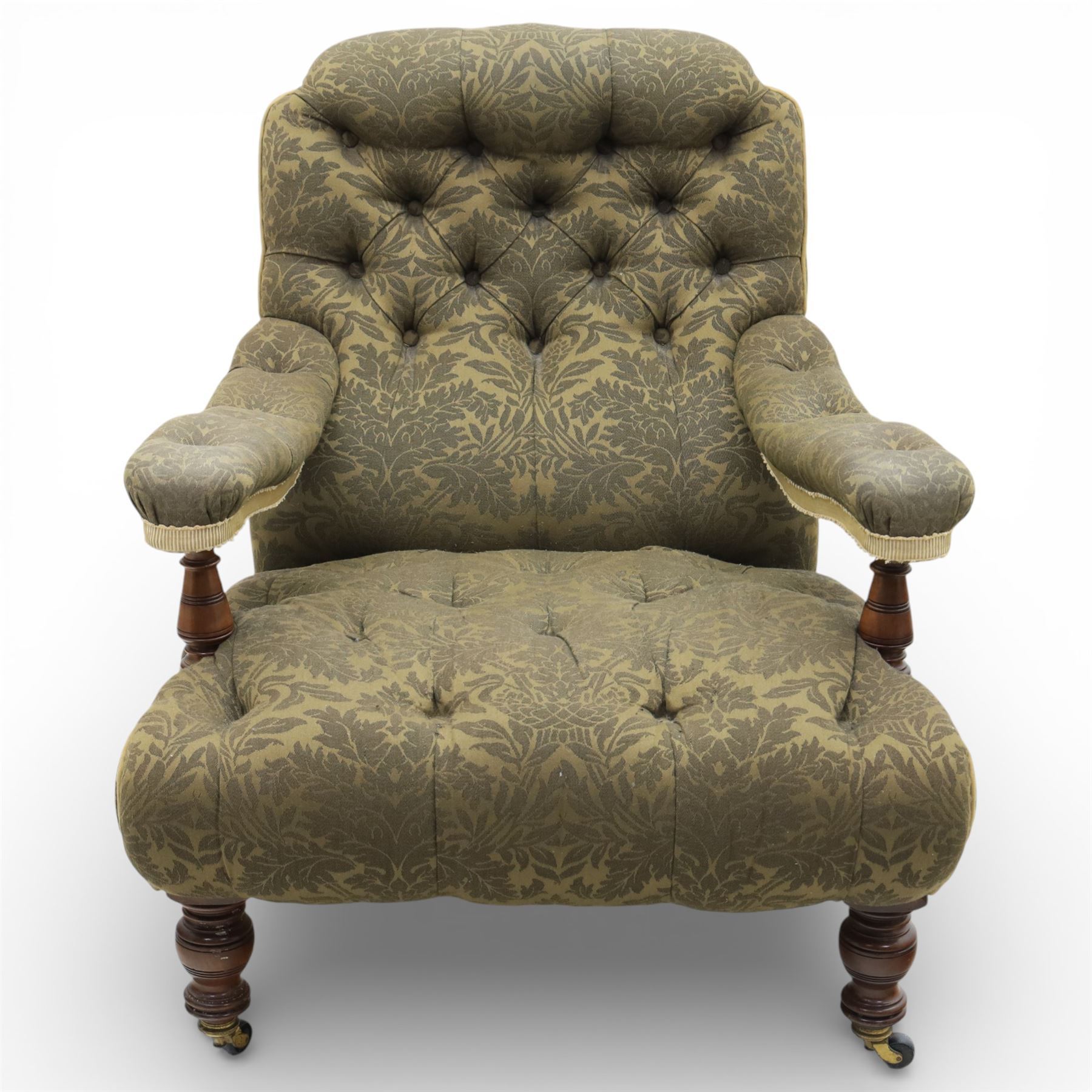 Late Victorian open armchair, in the manner of Howard & Sons, with deep buttoned seat and back upholstered in green damask fabric, with fringed detail to the lower arms, raised upon turned front legs with brass castors