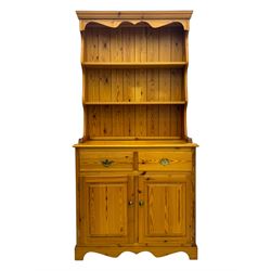 Victorian design pine dresser, projecting moulded cornice over scalloped frieze and two open shelves, base fitted with two drawers over double cupboard, on shaped plinth base