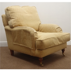  Lounge armchair, upholstered in a yellow fabric, walnut turned supports on castors, W85cm  