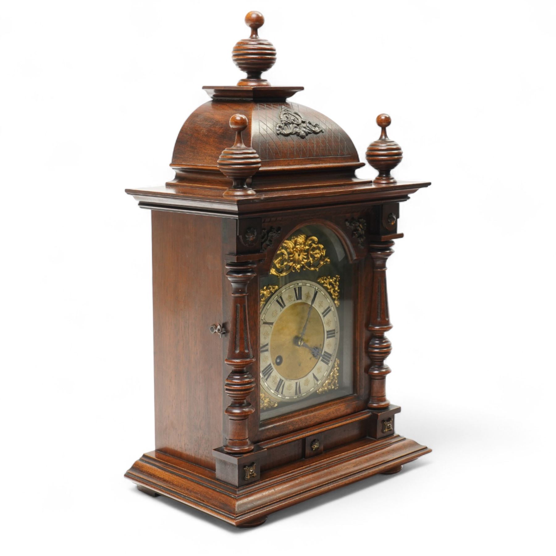 German-Junghans late 19th century oak cased mantle clock, with a domed pediment and three matching turned finials, break arch door beneath with attached turned and tapered pilasters, brass dial with cast spandrels, matted dial centre, steel hands and silvered chapter ring with Roman numerals, two train movement striking the hours and half-hours on a coiled gong. With pendulum and key.