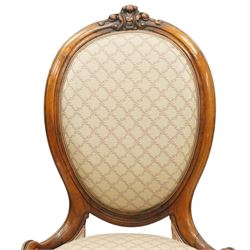 Pair of Victorian walnut framed ladies salon nursing chairs, oval cameo back with carved cartouche carved cresting rail, sprung seat upholstered in foliate patterned ivory fabric, shaped apron carved with scroll and cartouche decoration, on cabriole supports with moulded flower knees, retailed by David Hick Interiors, Jersey