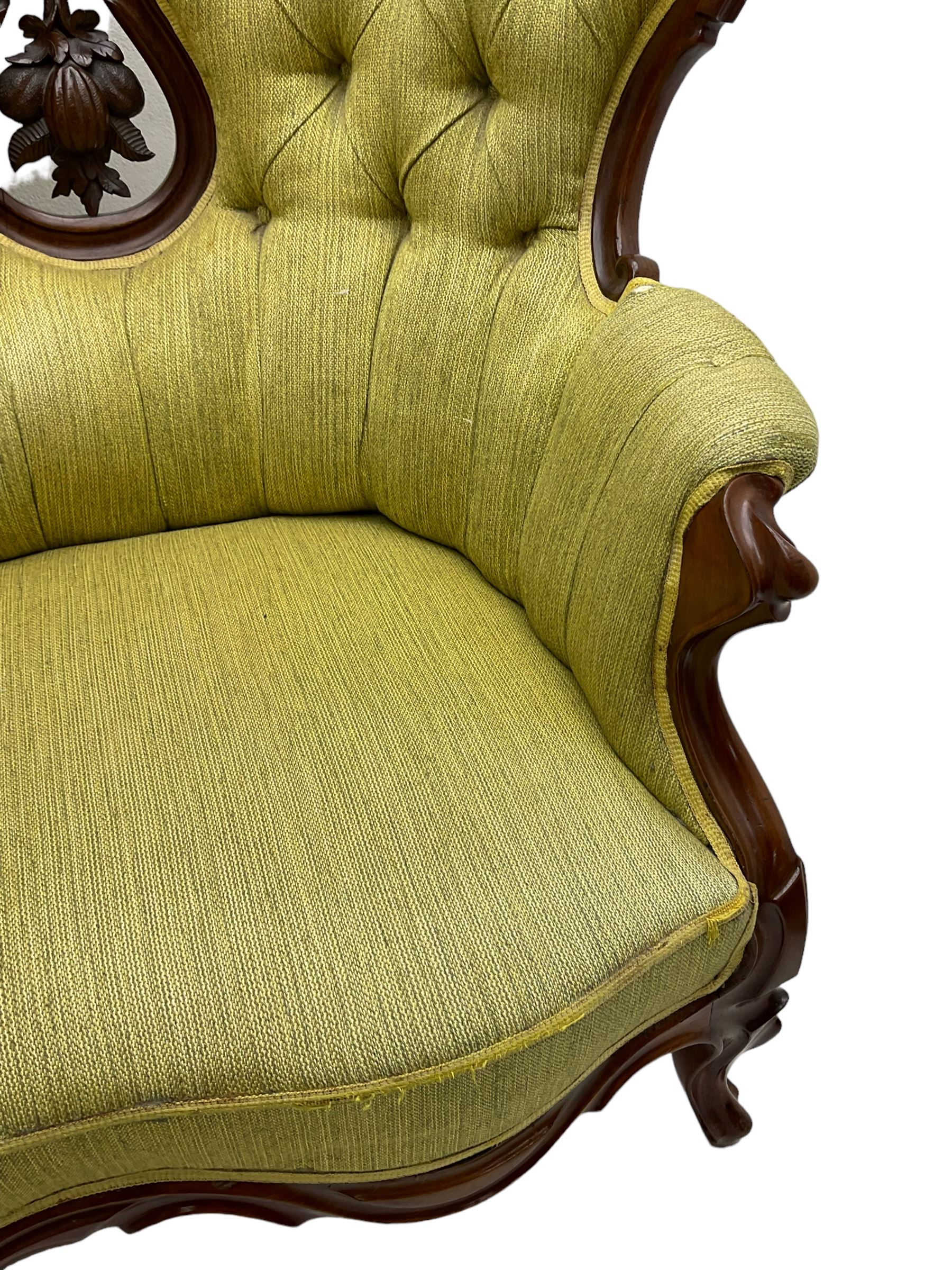 Victorian walnut settee, triple back with pierced and scroll-carved cresting rails over carved fruit and foliage decoration, upholstered in buttoned green fabric, serpentine seat and carved apron, on cabriole feet