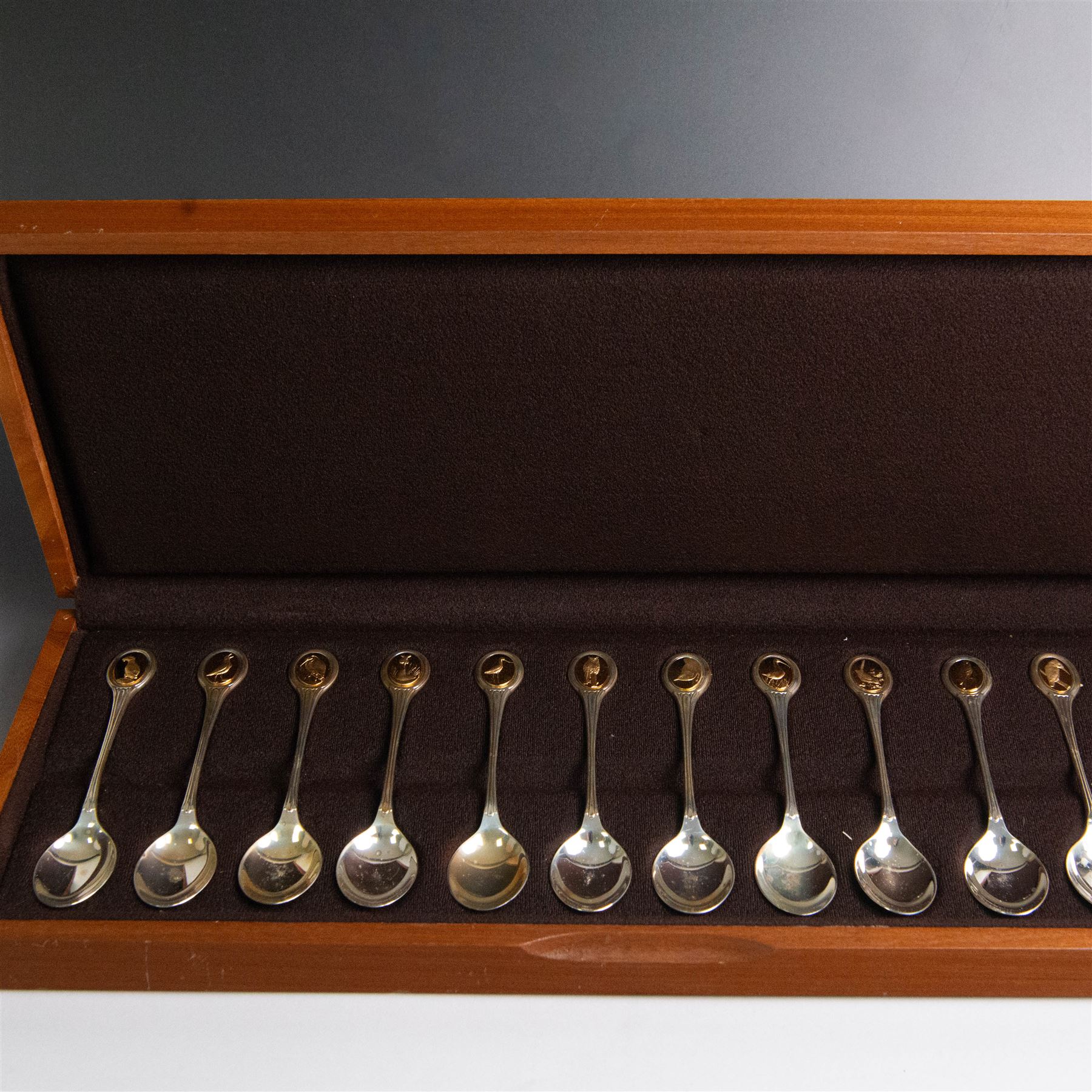 Royal Society for The Protection of Birds silver spoon collection, twelve spoons each inset with a silver-gilt bird cameo, hallmarked John Pinches Ltd, London 1975, in wooden presentation case with certificate of authenticity