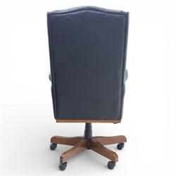 Chesterfield style desk chair upholstered in black, brass studded trim with tall button backed seat, with faux wooden base raised upon castors