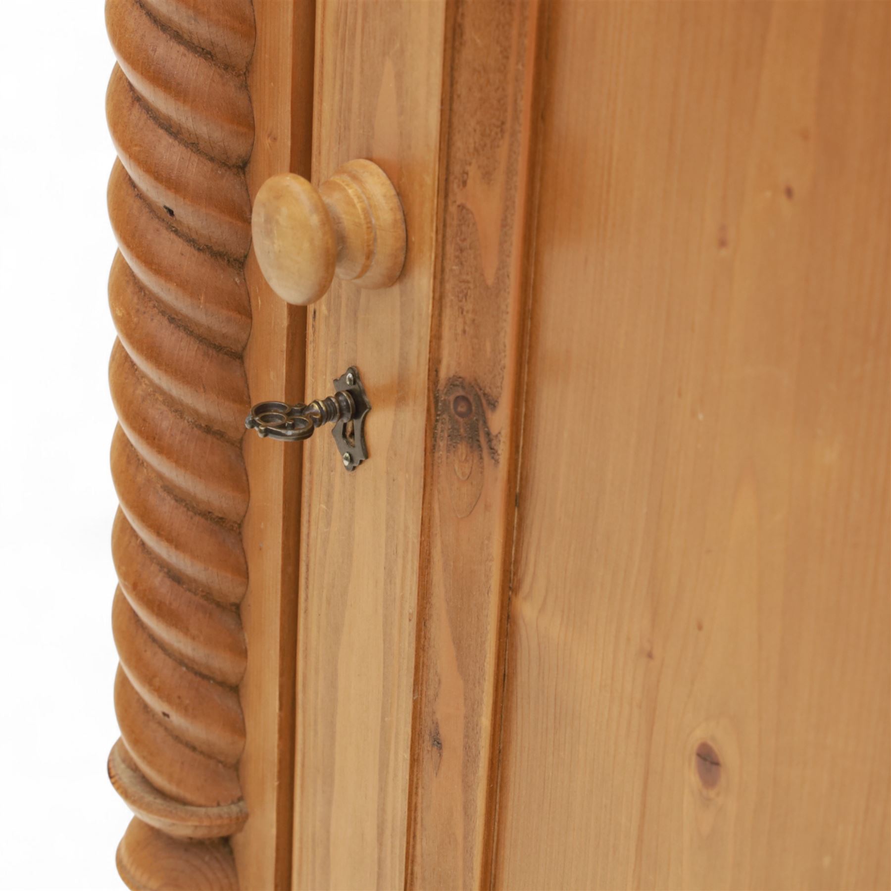 Contemporary stripped pine bookcase cabinet, the upper section with arched frieze and open shelving flanked by barley twist columns, over a single door cupboard base with matching twist supports and fielded panel door