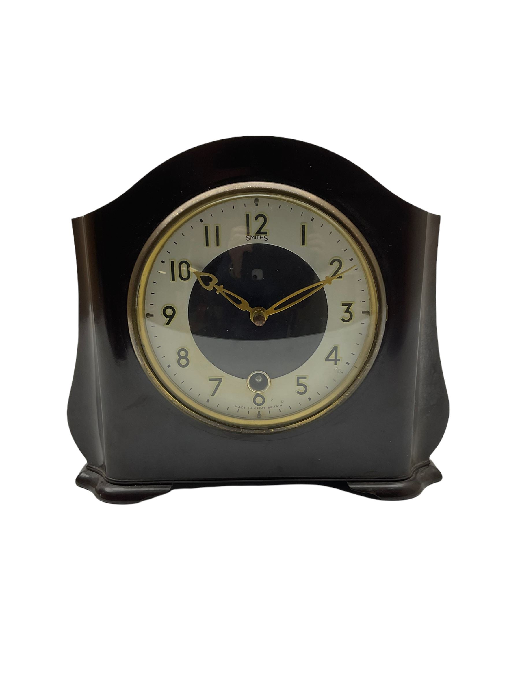 A Retro Art-Deco 1950's Bakelite cased mantel clock with a Smiths timepiece movement housed in a domed top case with curved sides on raised feet, dial with a cream chapter ring, upright Arabic numerals and minute markers, inscribed “Smiths, Made in Great Britain”, dial enclosed within a spun brass bezel and a convex glass, gilt pierced hands, spring driven 8-day pendulum movement. 
With pendulum.
