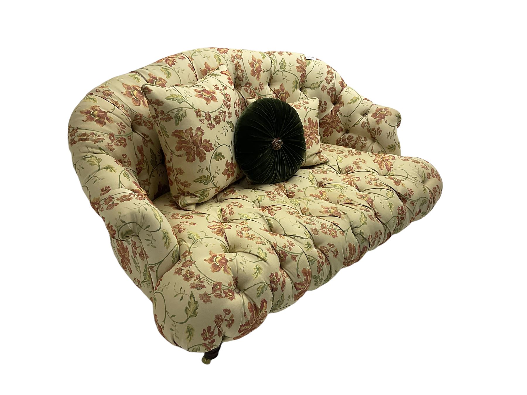 Victorian style two seat sofa, upholstered in beige ground floral floral pattern fabric, with scatter cushions, turned feet with brass castors