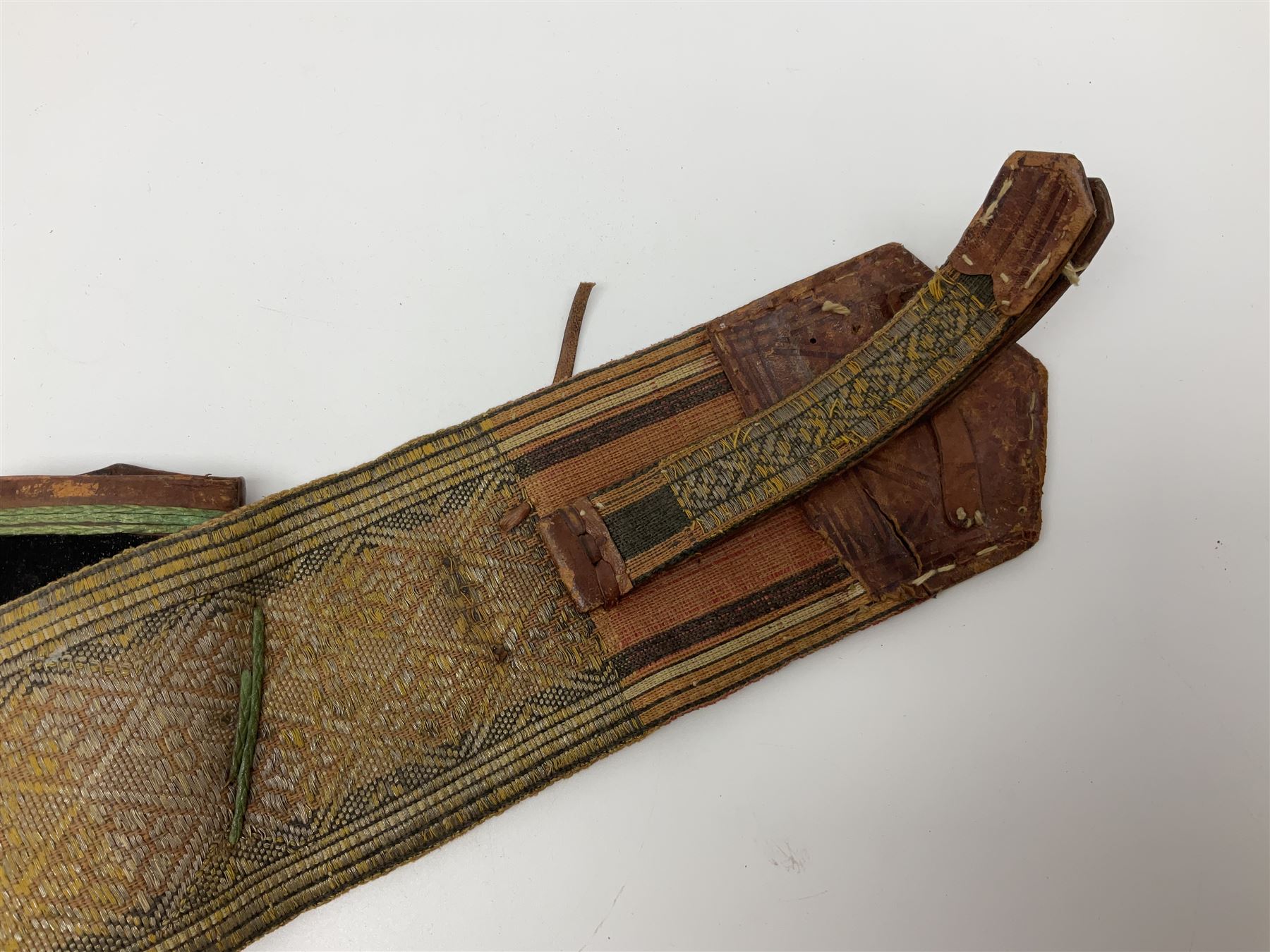 Late 19th century Yemeni Tuza jambiya as worn by religious elite, the 20.5cm curving blade with raised medial ridge, the horn hilt with pique style studwork, in a leather wrapped wooden scabbard with pierced metal mount and leather belt applied with embroidered 'gold' and 'silver' thread work panel; dagger L36cm overall, belt L84cm