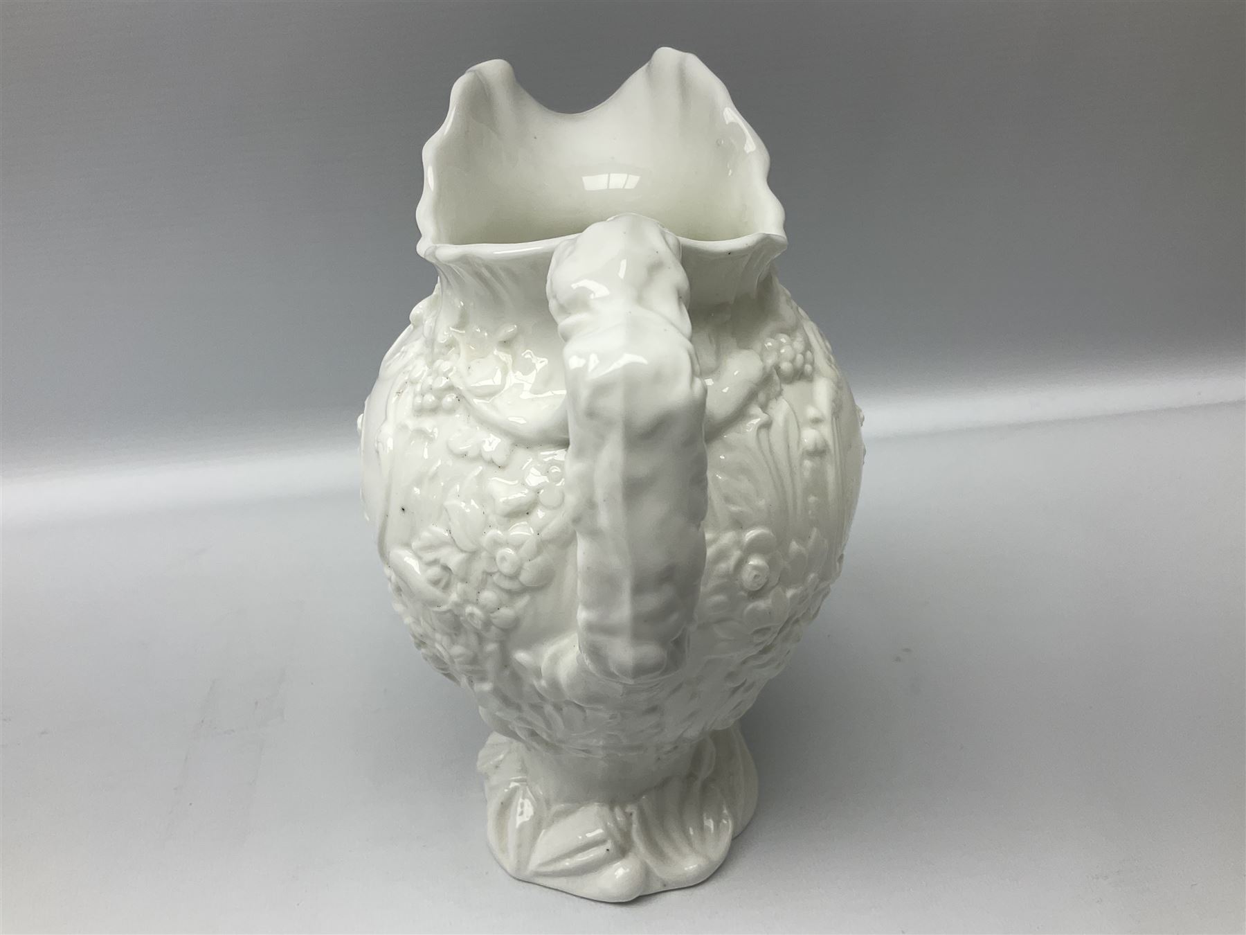 Pair of early/mid 19th century Copeland and Garrett white glazed pitchers, modelled in the Georgian style and moulded with the figures of Venus the Roman Goddess of Love, and Aurora the Roman Goddess of Dawn, within C scroll borders and foliate surround, the naturalistically modelled handle leading to a fruiting vine beneath the rim, upon a spreading base moulded with seashells, with printed green crowned wreath mark beneath, H20cm