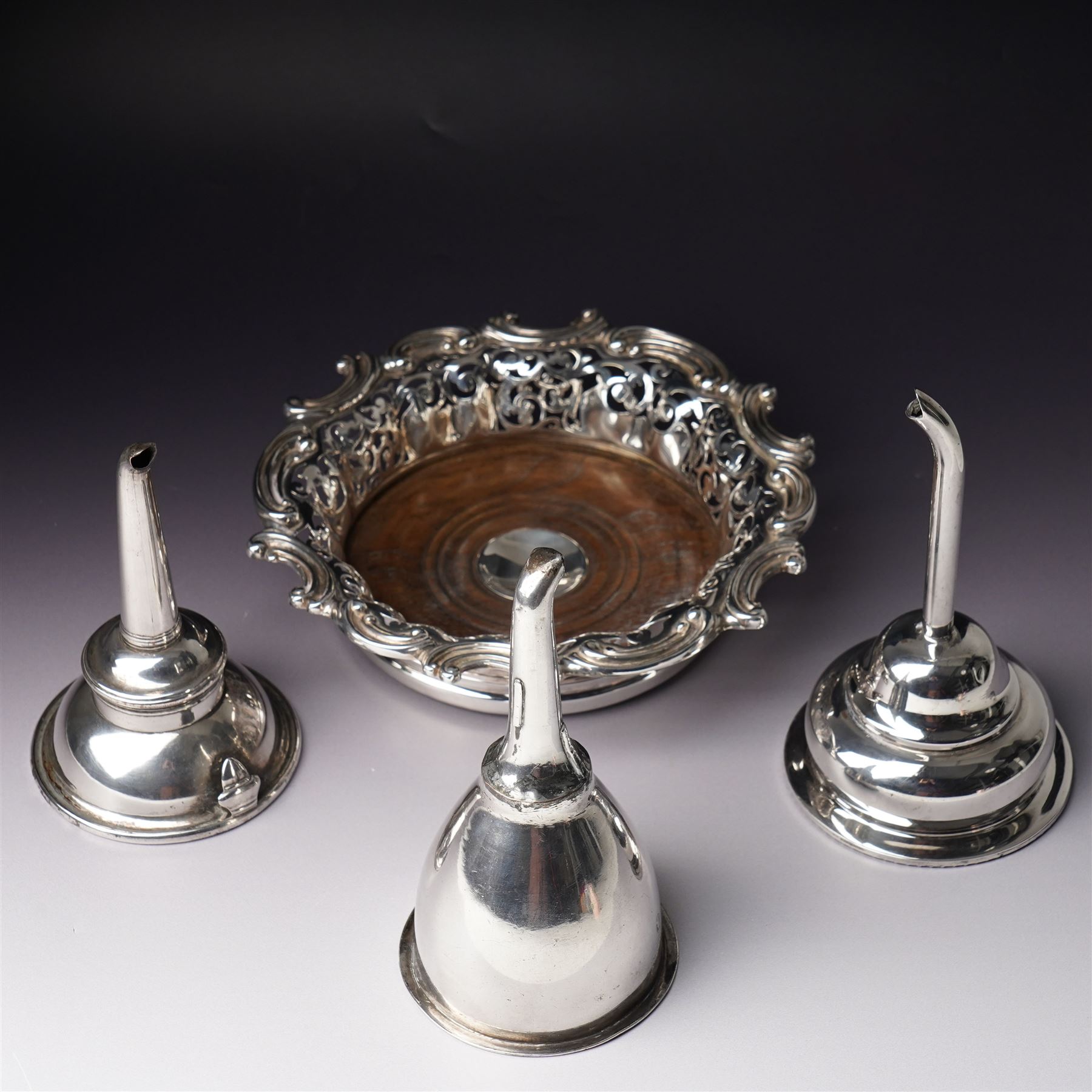18th century Sheffield plate wine funnel by Roberts, Cadman & Co with bell mark, two other plated wine funnels and a Victorian plated bottle coaster by Elkington & Co with pierced decoration and turned wooden base (4) 