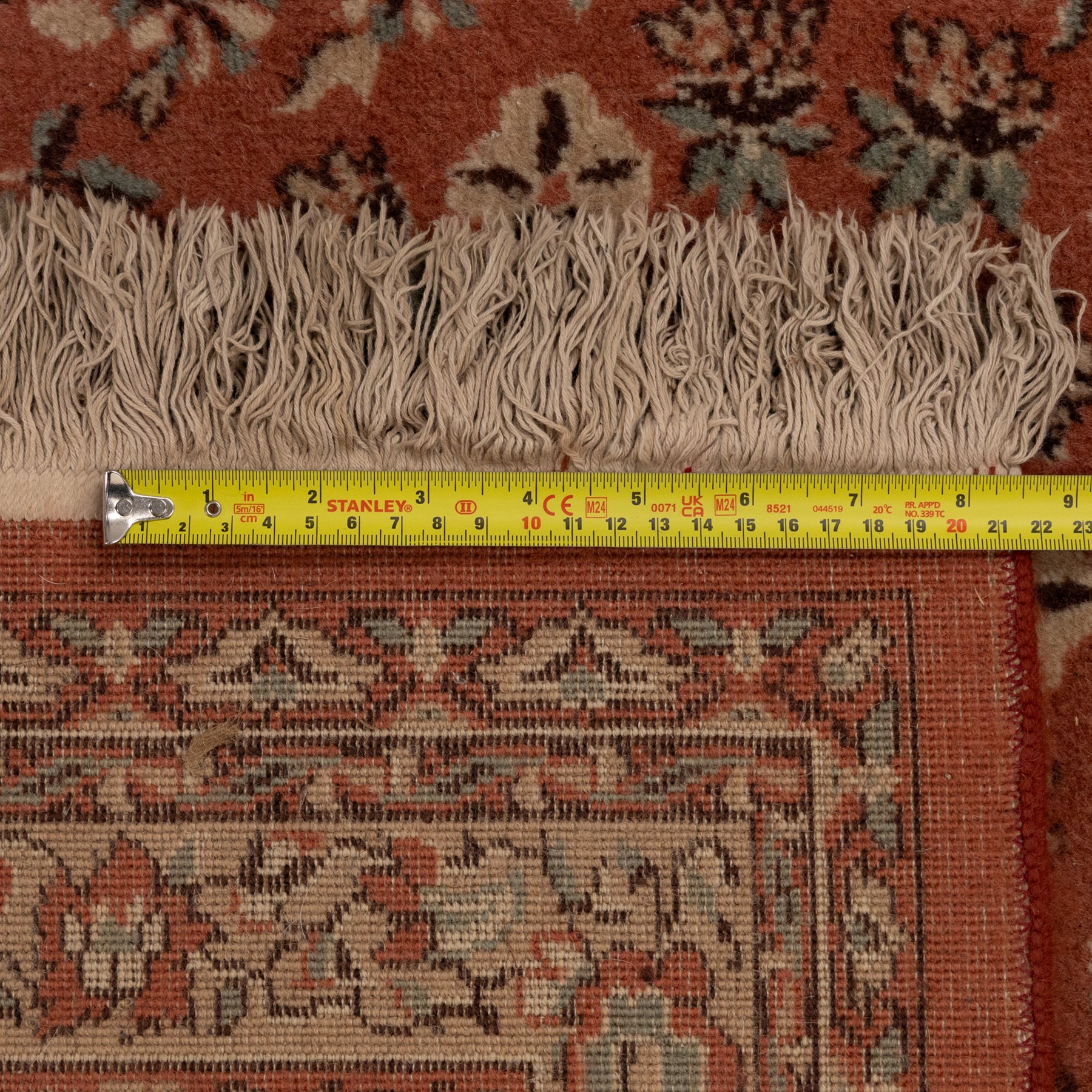 Persian vermillion ground Kashan rug, the busy field decorated with a central floral pole medallion, surrounded by trailing foliage and profusely woven floral patterns and bouquets, the dark indigo spandrels and multiple guard bands with similar floral decoration and stylised spandrels