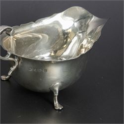 Group of early 20th century silver, comprising sauce boat, with flying scroll handle and upon three pad feet, two small cream jugs and a christening mug, all hallmarked, tallest H10cm