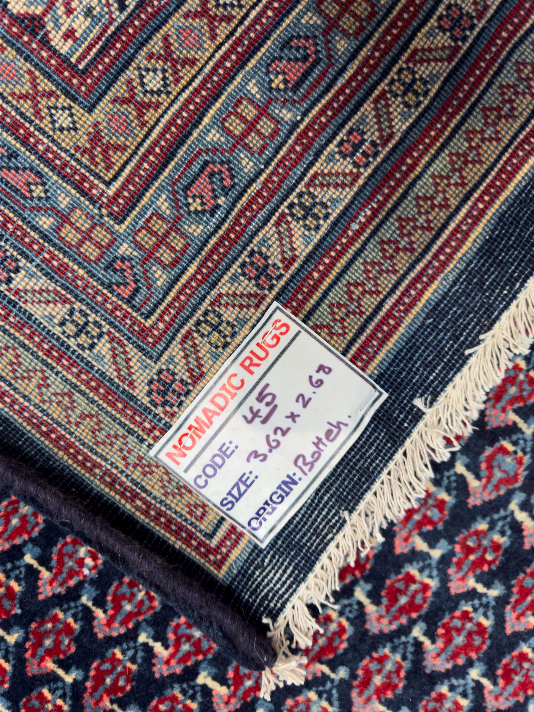 Northwestern Persian Bottehmir hand-knotted carpet, dark indigo field with an all-over design of boteh motifs arranged in diagonal rows, framed by multiple borders, main ivory border with stylized floral sprays between narrow geometric guard stripes, 362cm x 268cm