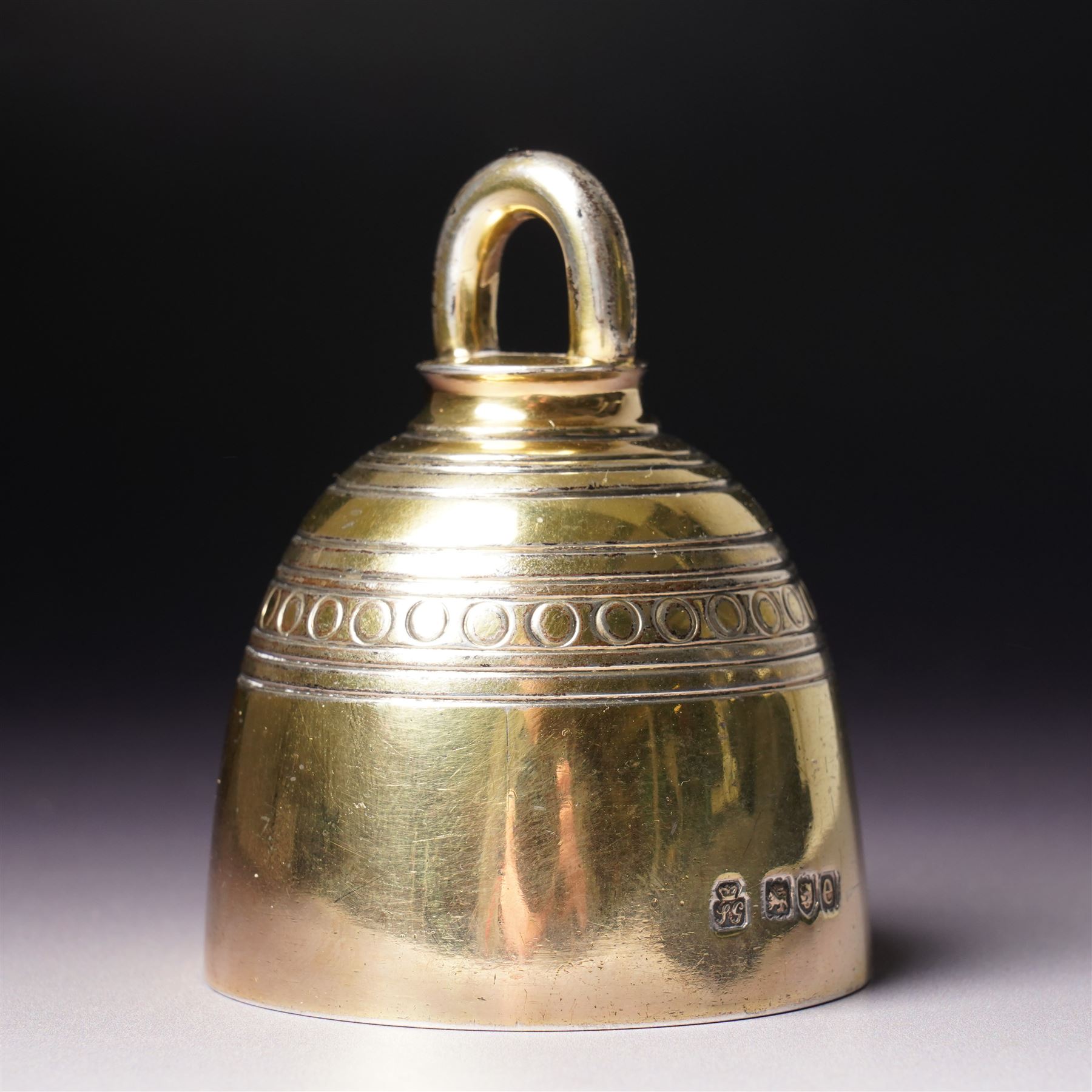 Late Victorian silver gilt table bell with reeded and roundel decoration and loop handle, bell and clapper both hallmarked H7cm London 1900 Maker R & S Garrard & Co