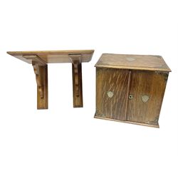 Early 20th century oak smokers cabinet, with brass shield shaped mounts, opening to reveal a compartmentalised interior with three drawers, pipe rack and tobacco jar, together with a small wooden shelf, smokers cabinet H28.5cm