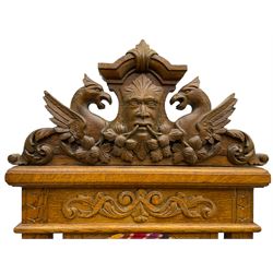 Set of six 20th century Carolean design oak high back chairs, the pediment carved with dragons and central Green Man mask with trailing foliage, the backs upholstered in striped fabric, on turned front supports