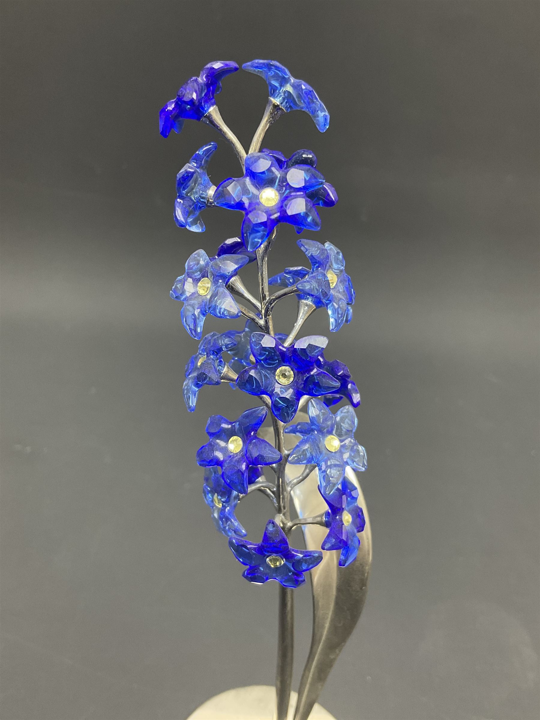 Eleven Swarovski Crystal flowers, to include violet, sunflower, delphinium, forget-me-not and lily-of-the-valley, each on stylised metal stems, tallest H23cm